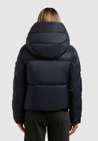 Marineblauwe pufferjack met een hoge kraag, geborduurd ontwerp en een cropped pasvorm. Beschikt over een grote capuchon en duurzaam materiaal met een gladde textuur.