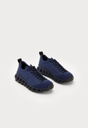 Navy blue athletic shoes with a textured knit upper, black rubber soles featuring a unique cushioned shape and lace-up design.