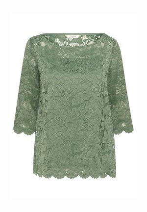 Green lace blouse with three-quarter sleeves, floral pattern, scalloped edges, and round neckline.