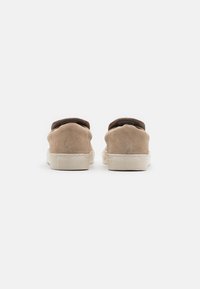 Beige Wildlederschuhe zum Hineinschlüpfen mit runder Zehenpartie und flacher, cremefarbener Gummi-Sohle. Minimalistisches Design ohne sichtbare Beschläge.