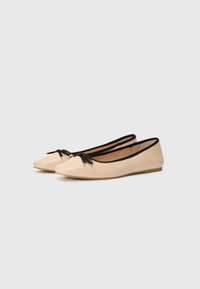Flat ballet shoes in beige with a glossy finish, pointed toe, and a black ribbon accent at the front. Soft, flexible material.