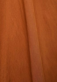 Cotton fabric in a warm orange-brown color, featuring a smooth texture and subtle diagonal weave pattern with visible stitching details.