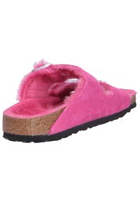 Pink open-toe slide sandal with a soft, fuzzy interior, suede exterior, cork midsole, and textured rubber outsole. Features a strap design.