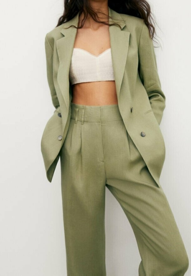 Light green tailored suit featuring a fitted blazer with two buttons and wide-leg trousers, crafted from a smooth, textured fabric.
