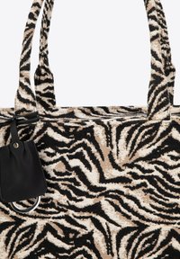 Borsa a tracolla con un motivo a righe zebra nero e beige, tessuto texturizzato e dettagli in pelle nera con un particolare anello argentato.