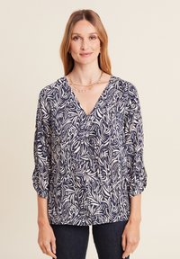 Marinebluse mit weißem abstraktem Blattmuster, V-Ausschnitt und Dreiviertelärmeln. Leichter Stoff mit lockerer Passform.