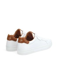 White sneakers with a smooth leather upper, brown leather accents at the heel, flat lace closure, and textured rubber sole.