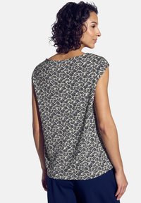 Top a maniche corte con motivo floreale in navy e crema, dalla vestibilità morbida e scollatura arrotondata. Tessuto liscio con dettaglio di texture sottile.