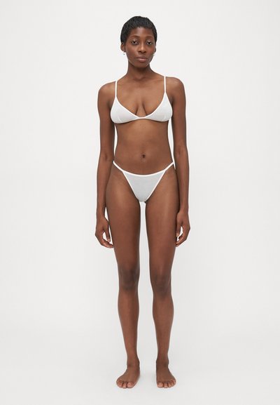 Balts bikini komplekts ar trīsstūra formu bikini topu un minimālu apakšdaļu. Izgatavots no gludas auduma ar plāniem siksniņām un vienkāršu dizainu.