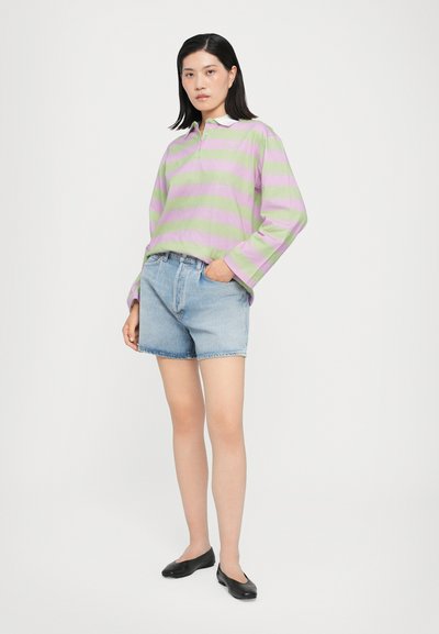 Striped long-sleeve polo in light green and lavender, paired with light blue denim shorts. Black flats complete the outfit.