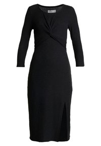 Svart ribbad klänning med långa ärmar, en vriden frontdetalj och en slits som går högt upp på låret. Tillverkad av texturerad tyg. Klassisk, figurnära silhuett.