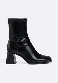 Schwarzer Knöchelstiefel aus glänzendem Leder mit Blockabsatz. Verfügt über eine strukturierte Sohle und ein spitzes Design. Nahtdetails im Obermaterial.