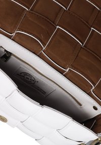 Borsa a mano in pelle intrecciata marrone e bianca con cerniera dorata e un’etichetta interna che riporta la dicitura "Made in Italy."