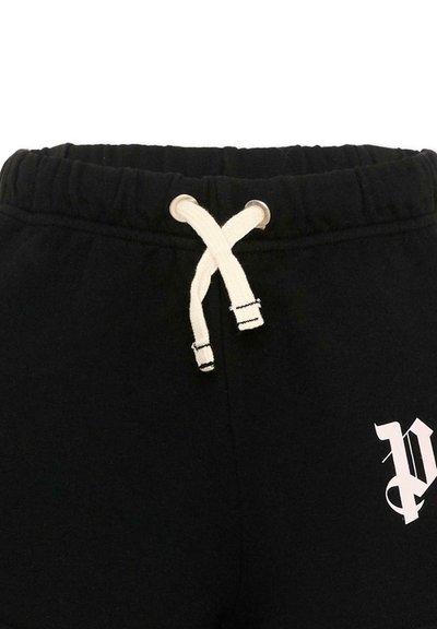 Pantalon de survêtement noir avec taille élastique, cordons blancs croisés, et une lettre "P" de style gothique blanc imprimée sur le côté droit.