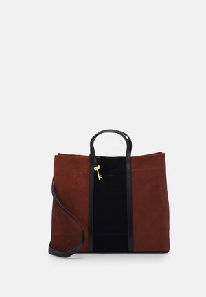 Brown and black suede tote bag with dual top handles, adjustable shoulder strap, gold key accent, and front logo detail.