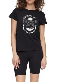 Czarny bawełniany t-shirt z krótkim rękawem, z białym graficznym wzorem przedstawiającym słońce i rośliny oraz tekst. Połączony z czarnymi szortami.