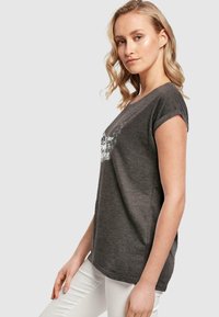 Mørkegrå T-shirt med korte ærmer, rund hals og en afslappet pasform. Har hvid tekstgrafik foran. Blød stoftekstur.