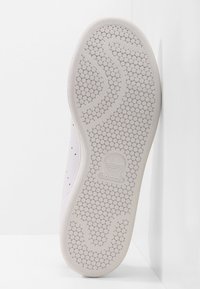 Vit sneakersula med hexagonalmönster, prydd med en präglad Adidas trefoil-logotyp och slät, texturerad kant.