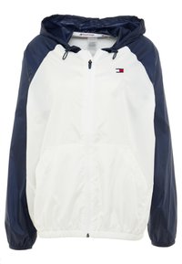 Giacca a vento bianca e blu navy con cappuccio, zip frontale, polsini elasticizzati e tasche laterali; presenta il logo Tommy Hilfiger.