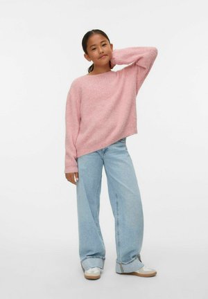 Pull en peluche rose clair avec un large col, une coupe ample et des manches longues, associé à un jean taille haute décoloré et des baskets blanches.