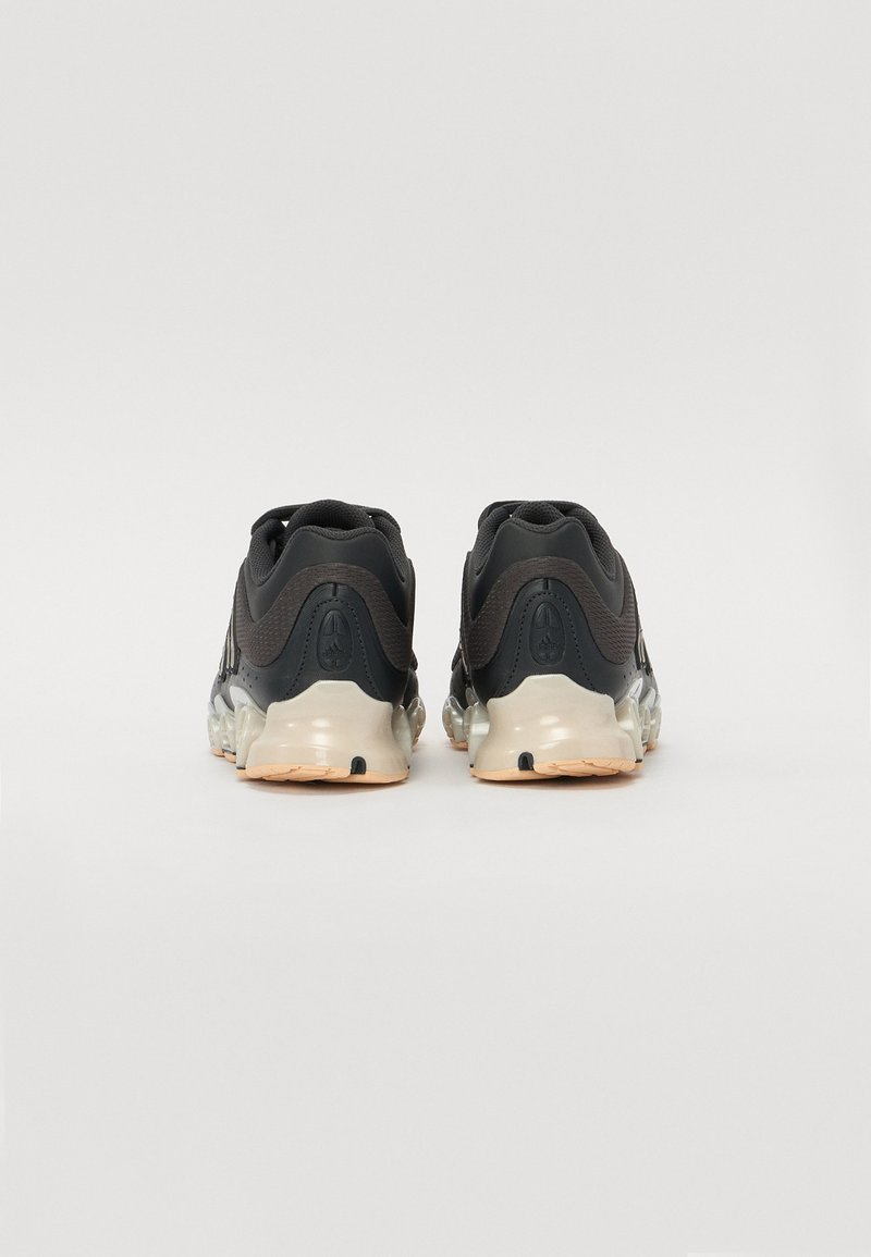 Zapatillas deportivas negras con un upper texturizado, suela transparente y soporte acolchado para el tobillo. Cuenta con una suela exterior beige en contraste para mayor agarre.