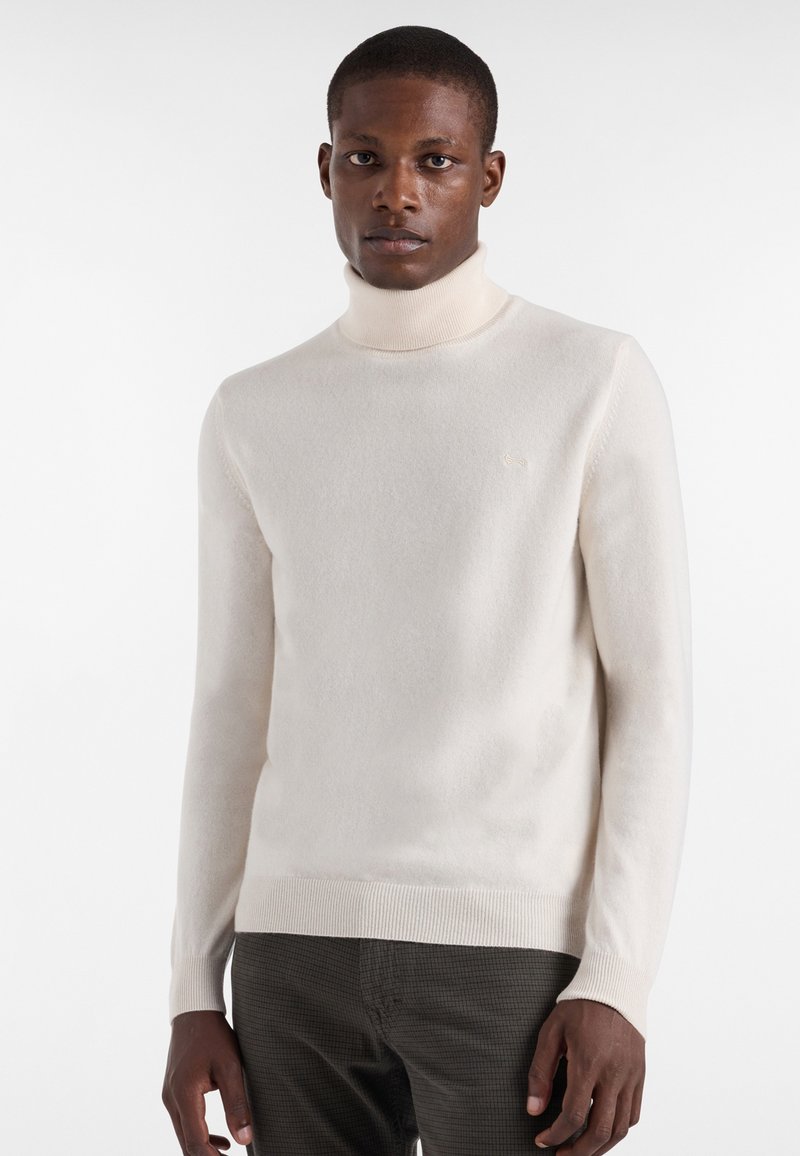 Kerman neule turtleneck, jossa on pehmeä rakenne, istuvat pitkät hihat ja ribattu helma. Edessä on hienovarainen logo rinnassa.