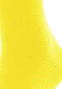 Helle gelbe Socke aus einem glatten, dehnbaren Stoff. Verfügt über eine verstärkte Zehenpartie, nahtloses Design und eine enge Passform am Knöchel.