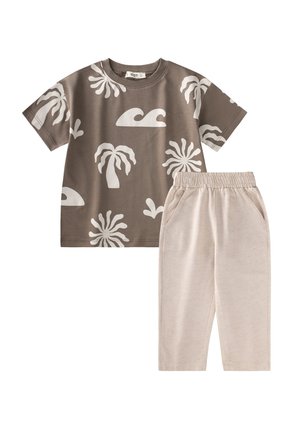 Braunes T-Shirt mit kurzen Ärmeln und weißen tropischen und Wellen-Prints, kombiniert mit hellbeigen Hosen mit elastischem Bund und Taschen.