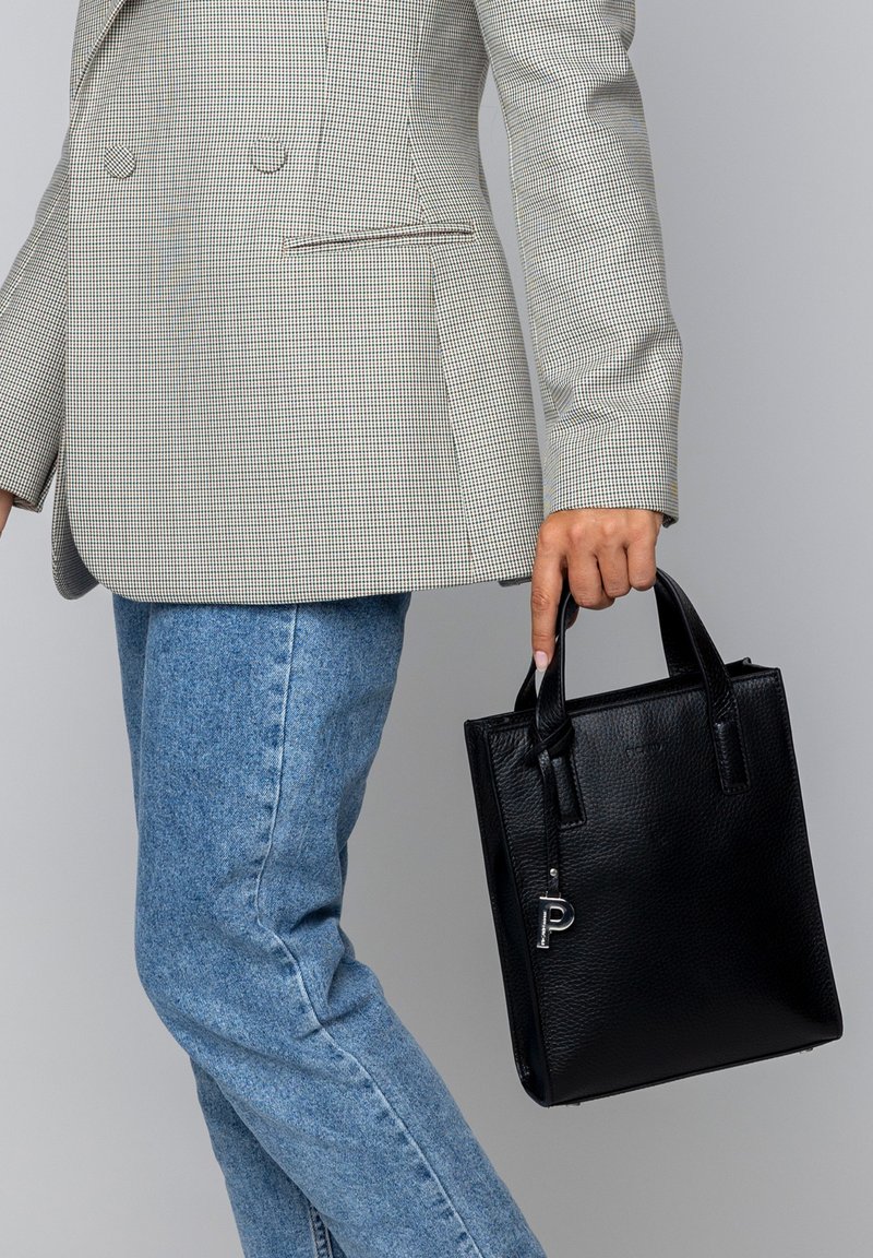 Black leather tote bag with textured finish, square shape, and short handles. Features a silver accent tag with the letter "P."