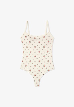Body côtelé couleur crème avec fines bretelles réglables et petit motif floral rouge sur l’ensemble.