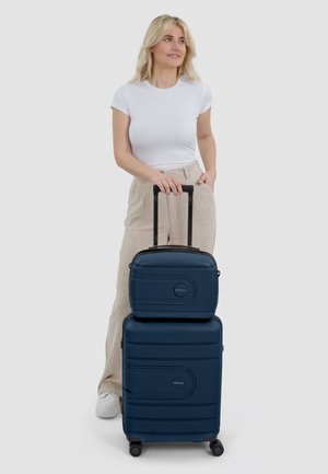 Un ensemble de bagages bleu foncé, présentant un extérieur lisse et texturé. Comprend un bagage à main et une valise plus grande avec des poignées rétractables et des roues.