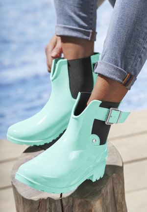 Mint green rubber ankle boots with black elastic side panels and a silver buckle detail, featuring a textured sole for grip.