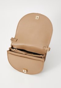 Beżowa skórzana torebka na ramię z zaokrąglonym klapkiem, złotym kwadratowym zapięciem, wewnętrzną kieszenią na zamek i gładką fakturą. Otwarty design ujawnia przestronną wnętrze.