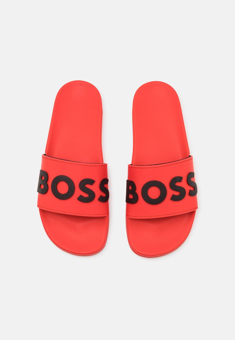 Rote Rutschsandalen mit schwarzer, fetter "BOSS" Schrift auf den Riemen, nebeneinander auf einem weißen Hintergrund präsentiert.