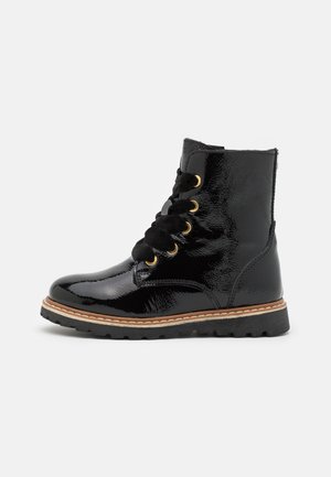 Black patent leather ankle boots with gold eyelets, lace-up design, padded collar, and rubber sole with textured tread.