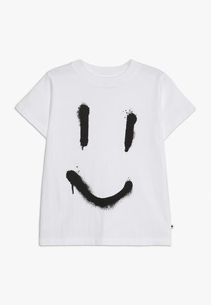 Hvid bomulds t-shirt med korte ærmer, der har et stort sort smilende ansigt som design, fremhævet med malingstænk omkring konturerne.