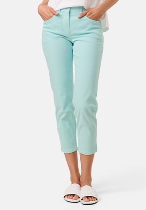 Light blue denim capri pants with two side pockets and a high waist. The fabric is smooth, and the hem is rolled up slightly. Worn with white slide sandals.