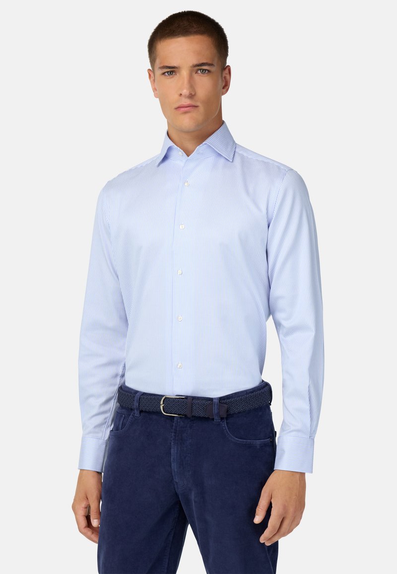 Gaiši zils garām piedurknēm krekls ar plānām baltām svītrām, ar pogu kakla un aprocēm. Apvienots ar tumši ziliem teksturētiem biksēm un atbilstošu jostu.