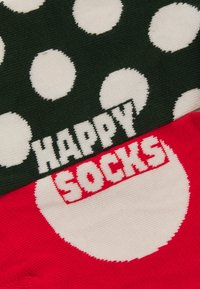 Coppia di calzini; uno verde con pois bianchi e la scritta "HAPPY", l'altro rosso con un grande punto bianco e la scritta "SOCKS". Materiale in cotone.