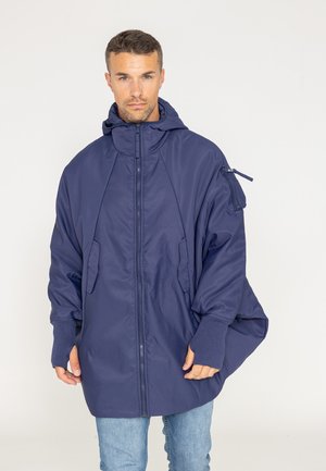 Veste oversize bleu marine avec capuche, fermeture éclair, poches latérales et poignets en tricot. Fabriquée en tissu léger avec une texture lisse.