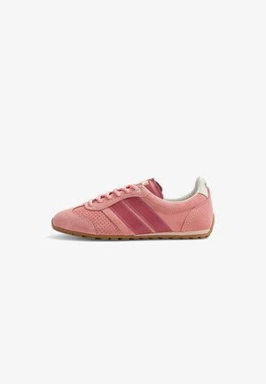 Baskets en daim rose avec des bandes rose plus foncé, semelle marron clair et lacets roses, vues de côté sur fond blanc.