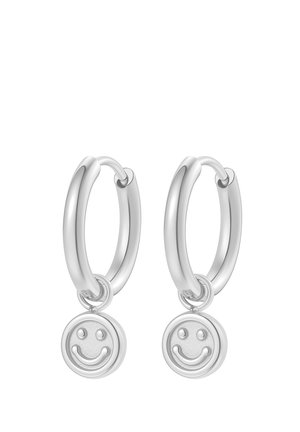 Silver hoop earrings with small dangling smiley face charms, polished and smooth finish, displayed on white background.