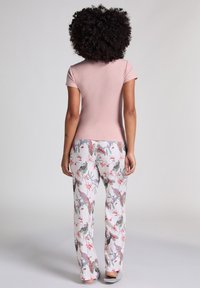 Kortärmad rosa topp och vita byxor med ett färgglatt blommönster, som har olika gröna och rosa mönster. Mjuk tyg, avslappnad passform.