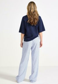Marine gebreide top met korte mouwen en lichtblauwe gestreepte wijde broek. Zachte textuur, losse pasvorm en casual ontwerp.