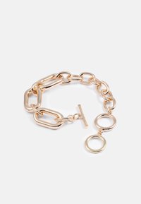 Bracciale in metallo dorato con maglie allungate e rotonde. Presenta una chiusura a battente e un dettaglio circolare pendente. Finitura liscia e metallica.