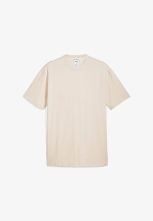 T-shirt en coton beige à manches courtes, col rond, avec un petit logo sur la poitrine. Texture lisse et coupe ample. Design simple.