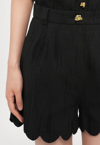 Schwarze Shorts mit einem strukturierten Muster, gewelltem Saum und goldenen Hardware-Akzenten. Sie verfügen über eine taillierte Taille und eine maßgeschneiderte Passform.