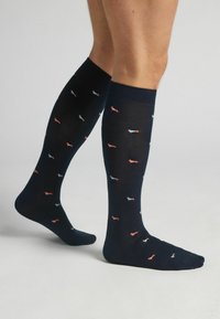 Ponožky po kolena z tmavé látky s hladkým povrchem, s opakujícím se vzorem malých modrých a červených psů.