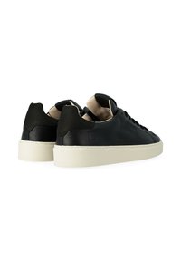 Sneaker in pelle nera con texture liscia, caratterizzate da un design low-top, fodera interna beige e suola in gomma crema.