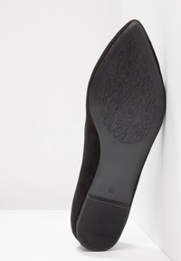 Chaussure noire à bout pointu avec une tige en daim, dotée d'une semelle en caoutchouc noir texturée et portant la taille 37 embossée. Présente un design épuré et minimaliste.